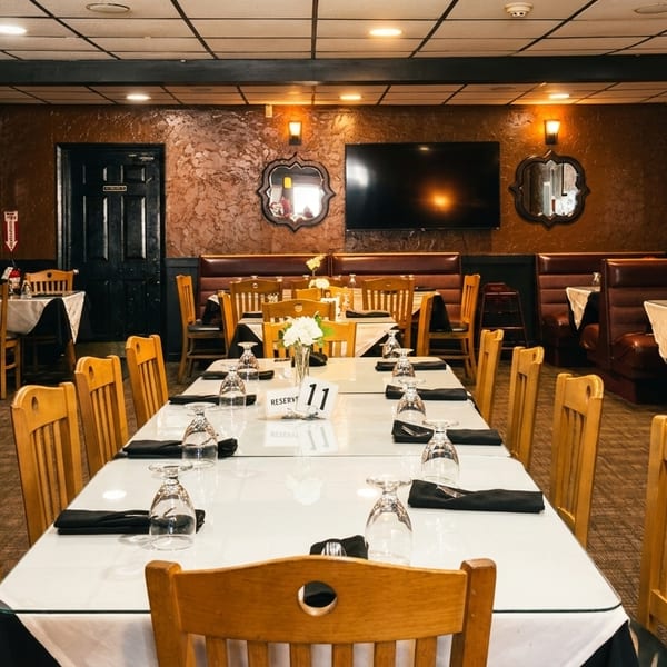 A restaurant dining room with a long reserved table and several booths with brown leather seating.